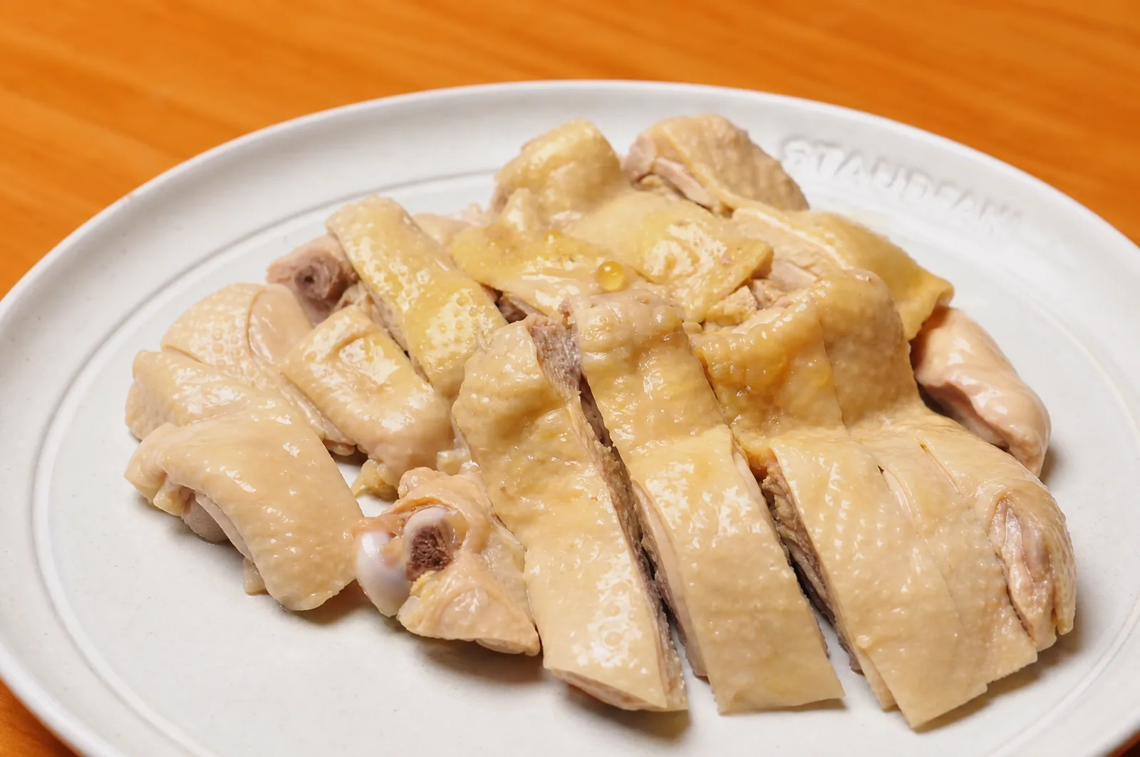 Sliced poached chicken served on a white plate without rice