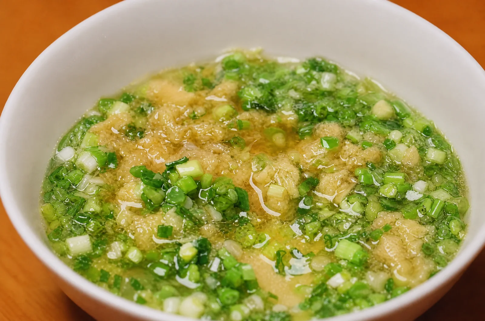 A close view of freshly chopped ginger-scallion sauce in a ceramic bowl